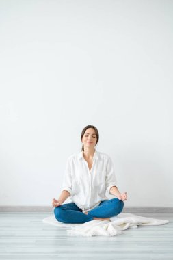 Genç kadın nilüfer pozisyonunda oturuyor. Evinde, parlak odasında..