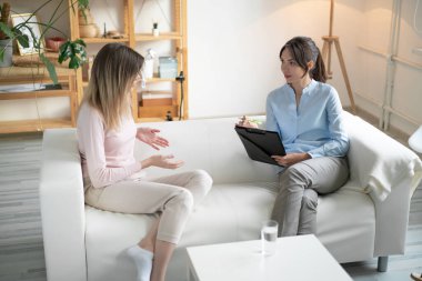 Hasta sorunlarını ofiste oturan psikoterapistle konuşuyor..