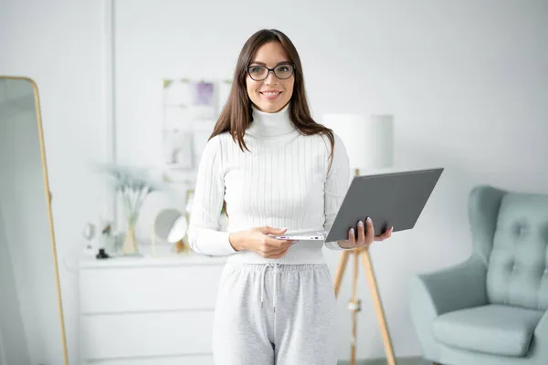 Young woman coach in glasses smile and stands with laptop.