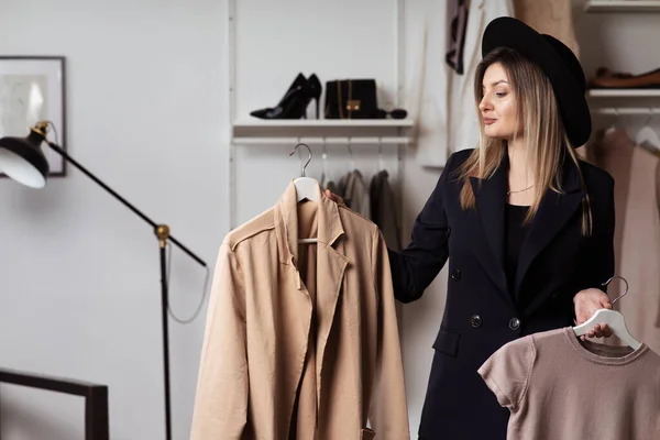 Young and beautiful woman stylist holds hanger with clothes in her hands. Selection and analysis of wardrobe.