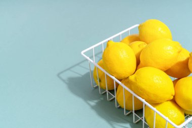 Açık yeşil renkli arka planda açık yeşil sepetli parlak sarı limonlar. Fotokopi alanı, ilkbahar vitamin eksikliği ve sağlıklı yaşam tarzı..