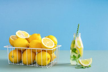 Olgun sarı limonlu beyaz sepet, limon ve nane dilimli bir şişe doğal limonata, doğallık ve tazelik vitamin konsepti..