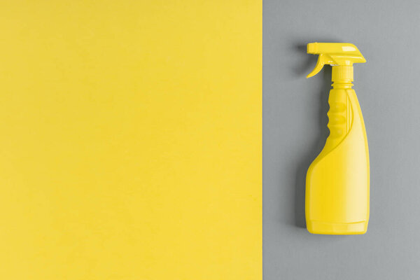 Спрей бутылка с бытовой химии для очистки, на сером фоне, желтый фон с копировальным пространством, концепция весенней очистки, 2021 популярных цветов.