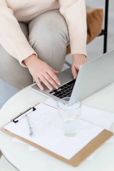 Dizüstü bilgisayarla yazı yazan kadınların yakın çekimleri. Online öğrenme kavramı. İnternette bir psikoterapistin işi. Masanın üzerinde bir bardak su ve bir pano var. Kısa süreli manikür..