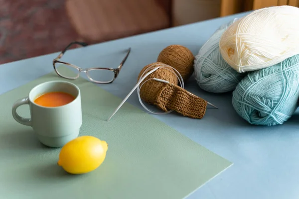蓝色桌子上有毛织线 针织针 茶和眼镜 含维生素的健康茶 老年人的业余爱好 — 图库照片