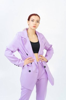 Mor takım elbiseli, siyah bluzlu, kızıl saçlı Asyalı bir kadın kameraya bakar. Siyah düğmeler. Modaya uygun kadınlar. Stüdyoda poz vermek.