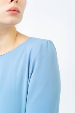 Mavi yazlık elbise ya da gömlek giymiş bir kadının omzuna. Yakın plan. Doğal kumaştan yapılmış giysiler. Beyaz arkaplan.