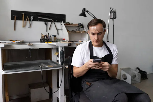 Hombre Trabajador Taller Sienta Una Pantalla Teléfono Inteligente Ocio Durante —  Fotos de Stock