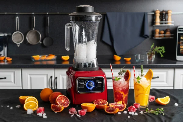 Parçalanmış buz küpleriyle modern elektronik kırmızı blender ve kartondan kokteyl tüpleri ile el yapımı limonata. ev mutfağı geçmişi.