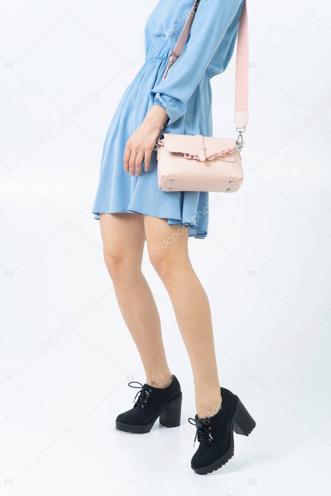 A woman in a light blue summer dress and black shoes, a beige small bag with a large chain. Summer image. Without a face. White background