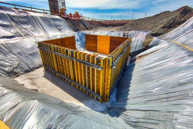 Köprü temelinin resmi işi derin bir kazıda gömülüdür, bu kazının yamaçlarında folyo vardır..