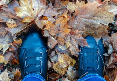 Sonbahar yeşilliklerinde siyah çizmeler