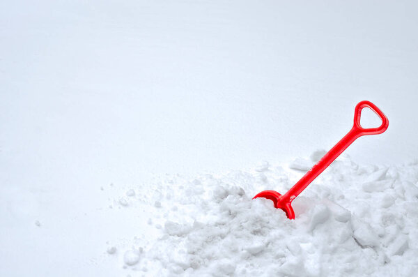 A red shovel stuck in a mountain of snow