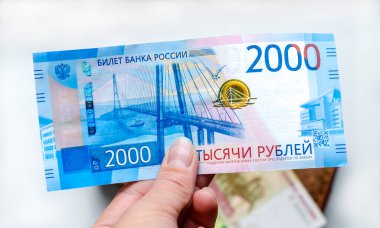 Bir kadının elinde 2000 ruble değerinde bir Rus banknotu diğer banknotlarla birlikte kahverengi bir cüzdanın arka planına karşı. Finans, yatırım, tasarruf ve nakit kavramı.