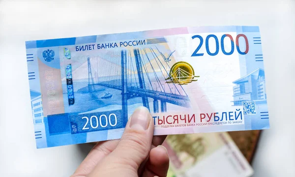 Bir kadının elinde 2000 ruble değerinde bir Rus banknotu diğer banknotlarla birlikte kahverengi bir cüzdanın arka planına karşı. Finans, yatırım, tasarruf ve nakit kavramı.