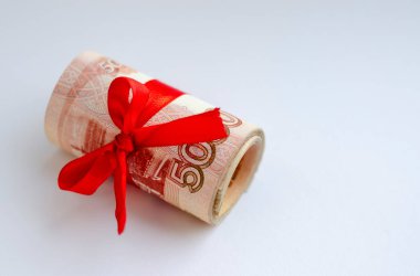 Kırmızı saten bir kurdeleyle bağlanmış, açık arkaplanda 5000 ruble değerinde Rus parası. Finans, yatırım, tasarruf ve nakit kavramı.