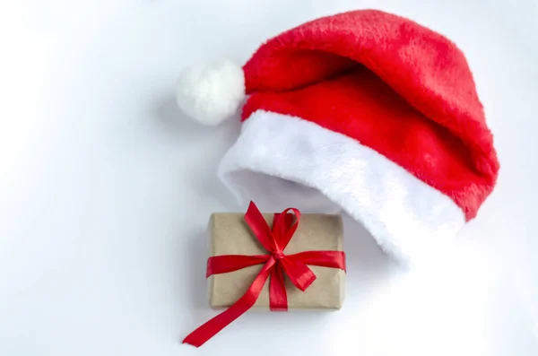 Eine Geschenkbox Mit Einem Roten Satinband Und Einem Weihnachtsmannhut Auf — Stockfoto