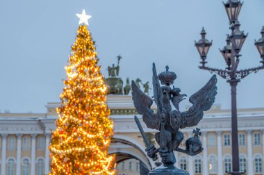 Alexander Sütunu 'nun çitindeki çift başlı kartal, Rusya' nın St. Petersburg kentindeki Palace Meydanı 'ndaki ana Noel ağacının arka planına karşı.