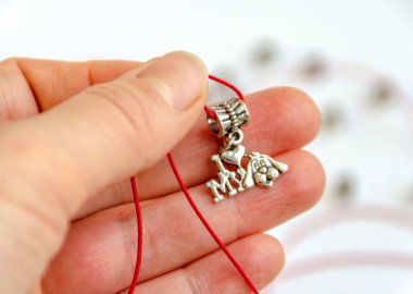 Kolye kırmızı bir ipliğin üzerinde. Elimde 