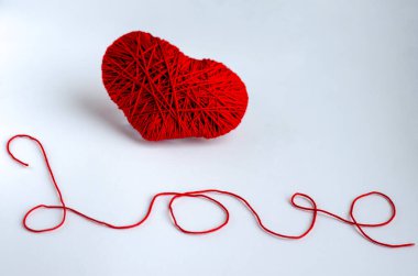 Kırmızı bir kalp ve iple yazılmış bir aşk. Yaratıcılık ve hobi kavramı. Sevgililer Günü tatili.
