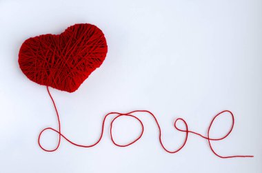 Kırmızı bir kalp ve iple yazılmış bir aşk. Yaratıcılık ve hobi kavramı. Sevgililer Günü tatili.