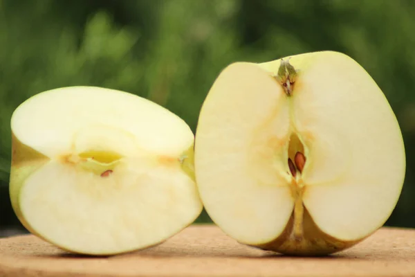 Two halves of an apple of the Zarya Alatau variety are rounded-conical in shape, the flesh is cream-colored on the cut.