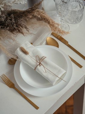 Beyaz Tabaklar, Kristal Gözlükler, Peçeteler, Altın Yiyici Utensil ve Kurumuş Çiçek Buketi Bir Vazo İçinde veya Bir Restoranda Kurutulmuş Bir Masa Görünümü