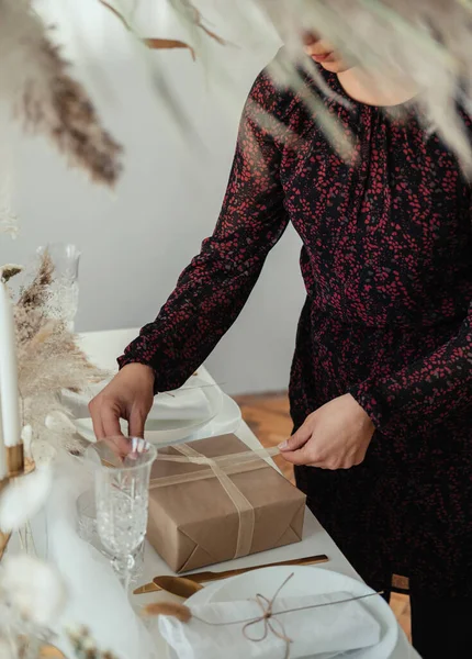 エレガントなランチパーティーを開催し クリスマスプレゼントを作る認識できない女性 ドレスの匿名の女性がテーブルを設定し 自宅でクリスマスディナーパーティーのための贈り物を準備 — ストック写真