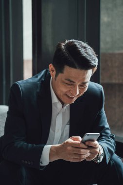 Yakışıklı Asyalı İş Adamı Kafe 'de Belgeler Okuyor. Mavi takım elbiseli ciddi bir iş adamı büyük pencerelerin yanındaki kafede otururken iş raporlarını tutuyor ve analiz ediyor..