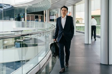 Yakışıklı Asyalı İş Adamı Kafe 'de Belgeler Okuyor. Mavi takım elbiseli ciddi bir iş adamı büyük pencerelerin yanındaki kafede otururken iş raporlarını tutuyor ve analiz ediyor..