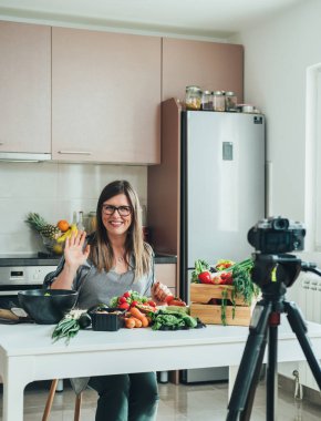 Gülümseyen Kadın Evde Çevrimiçi Aşçılık Dersinin Video Kayıt Dersi. Mutlu kadın şef el sallıyor ve merhaba diyor ya da youtube yemek kanalı için bir içerik çekerken elveda diyor..