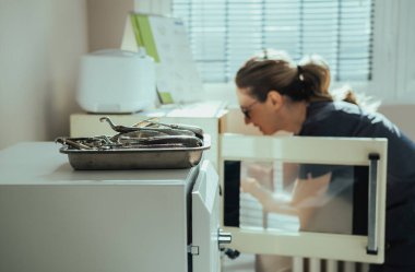 Diş Kliniği 'nde diş hekimlerinin sterilizasyonunu yapan isimsiz bir dişçi asistanı, diş aletleriyle çelik tepsiye odaklan