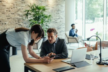 Kurumsal İş: İki Meslektaşımız Cep Telefonu Bakıyor ve Modern Açık Planlama Ofisinde Birlikte Tartışıyorlar