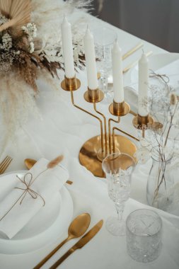 Evde Noel arifesi kutlaması için dekore edilmiş yemek masası. Yukarıdan, vazolarda, kristal bardaklarda, tabaklarda, peçetelerde, altın yemek kabında ve restoranda mumları olan şamdanlıklarda çiçek aranjmanlarıyla hazırlanmış lüks masa resimleri..