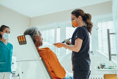 Diş implantı için diş izi ya da dişçi muayenehanesinde mutlu kadın diş hekimlerinden oluşan bir takımla taç taktırmak.