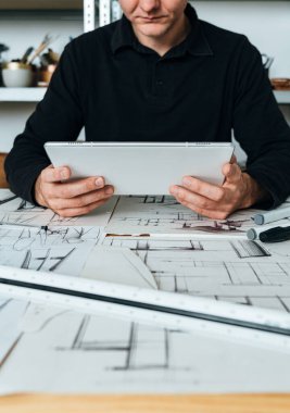 Ofisinde Mimar Elleri Dijital Tablet Tutma ve Bakım İnşaat Projesi 'nin Yakın Çekim Fotoğrafı. Tanımlanamayan mühendis masasında oturuyor ve yeni bir proje üzerinde çalışırken dijital tablet kullanıyor..