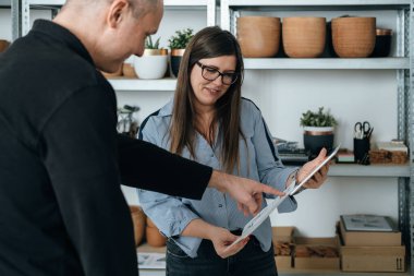Mutlu Mimarlar Ekibi Yeni Bir İş Projesinde Birlikte Çalışıyor. Yeni fikirler hakkında konuşan ve elinde planlar ve dijital tablet tutan kadın ve erkek mobilya tasarımcıları veya mühendis..