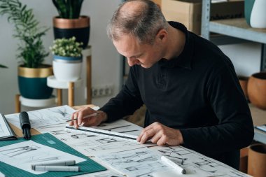 Başarılı Mimar, ofisinde yeni bir iş projesi üzerinde çalışıyor. Ciddi mobilya tasarımcısı, işyerinde kağıt, kalem ve cetvel kullanarak bitki standı tasarımı çiziyor..