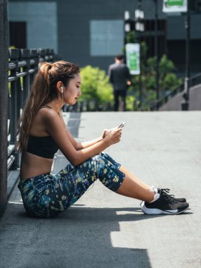 Spor Giyim 'de gülümseyen kadın açık havada cep telefonu kullanıyor.