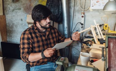 Mühendis atölyesinde Robot Kolunu İncelemek için Dijital Tablet kullanıyor