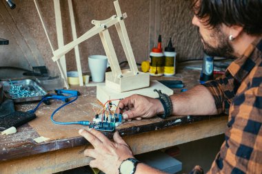 Robot Kol üzerinde çalışan isimsiz bir mühendis. Adamın eli telleri tutarken ve atölyesinde robot kol yaparken yakın plan fotoğrafı..