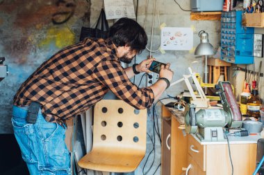 Anonim bir mühendis atölyesindeki akıllı bir telefondan robot kolunun fotoğrafını çekiyor.