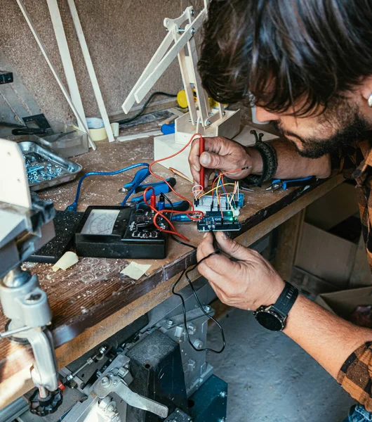 Atölyesinde robot kolu üzerinde çalışan isimsiz bir mühendis. Çoklu metre kullanan ve robotik koldaki voltajları kontrol eden tanınmayan bir adam.