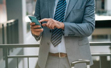 Havaalanında cep telefonunu kullanan anonim bir iş adamı. Terminalde dururken telefonuna mesaj yazan adamın fotoğrafını kapat..
