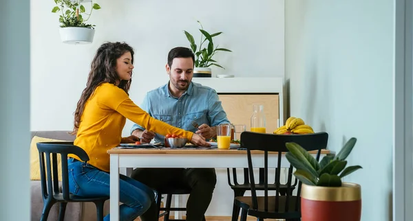 幸せなカップル一緒に自宅で朝食を食べる ダイニングルームで朝食を食べながら話している夫婦の笑顔 — ストック写真