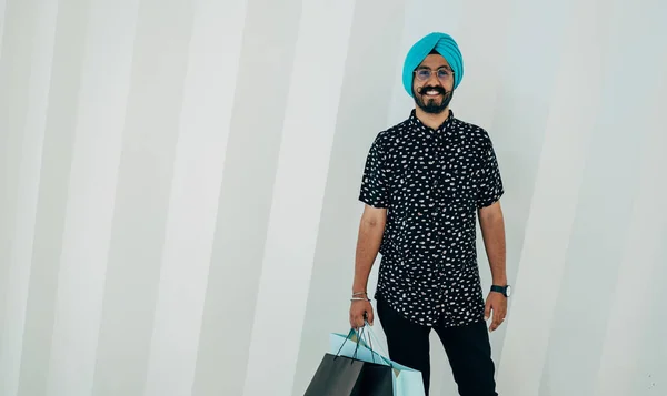 Portrait Of A Happy Man Holding Shopping Bags While Standing In Front Of White Background