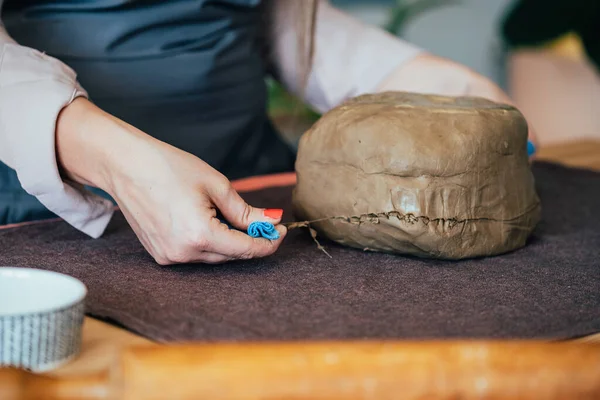 Küçük işletme: Tanımlanamayan kadın stüdyosundaki bir masa üzerindeki kilden bir parça kesiyor