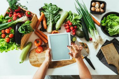 Kadın Ellerinin, Organik Sebzelerle dolu bir masanın üzerinde Dijital Tablet Kullanımının Fotoğrafını Kapat