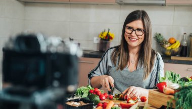 Mutlu kadın şef youtube kanalı için sağlıklı salata ve öğle yemeği hazırlama videosunu kaydediyor.