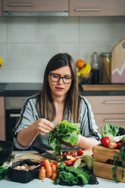 Önlüklü Güzel Kadın Mutfak Masasında Otururken Taze Marul Tutuyor